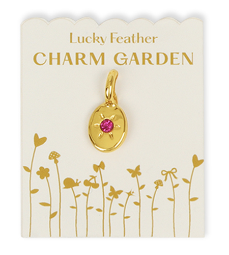 A golden charm with a pink gemstone is attached to a Lucky Feather Charm Garden card.