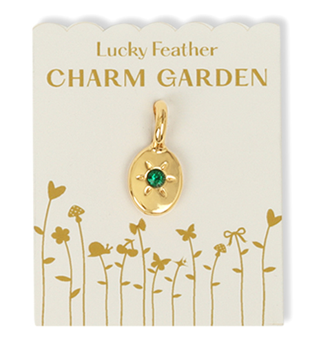 The image shows a "Lucky Feather Charm Garden" charm with a gold oval pendant and a green gem on a decorated white card.