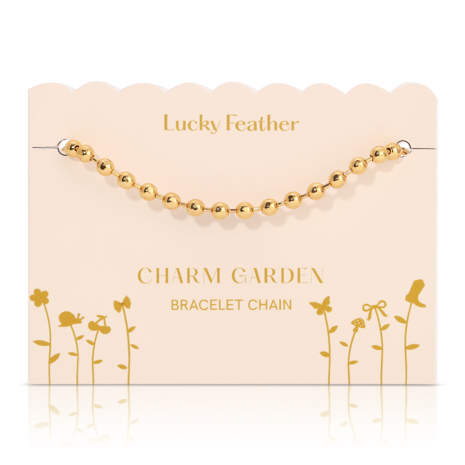 A gold bead bracelet chain on a decorative 'Lucky Feather Charm Garden' display card.