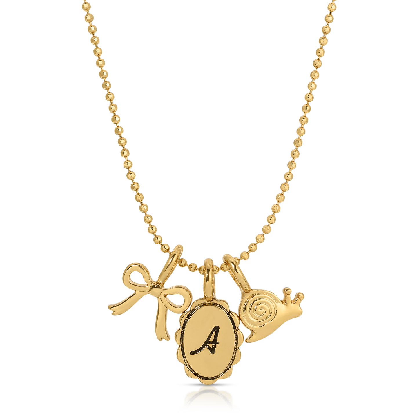 A gold ball-chain necklace features charms of a bow, an "A" initial pendant, and a snail.