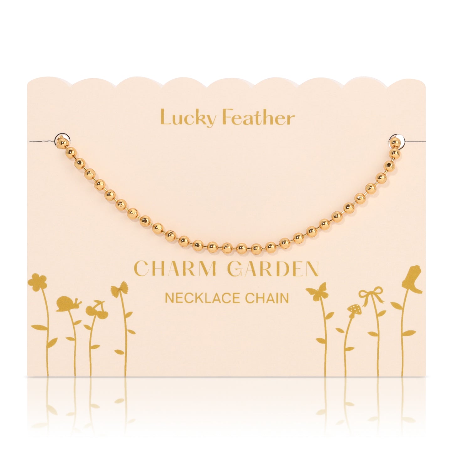 A gold-colored ball chain necklace is displayed on a peach-colored card with the words "Lucky Feather Charm Garden Necklace Chain" and gold floral silhouette graphics.