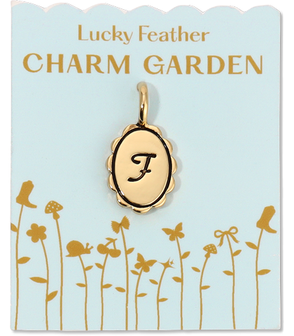 A gold charm with the letter "F" on a card that reads "Lucky Feather Charm Garden."
