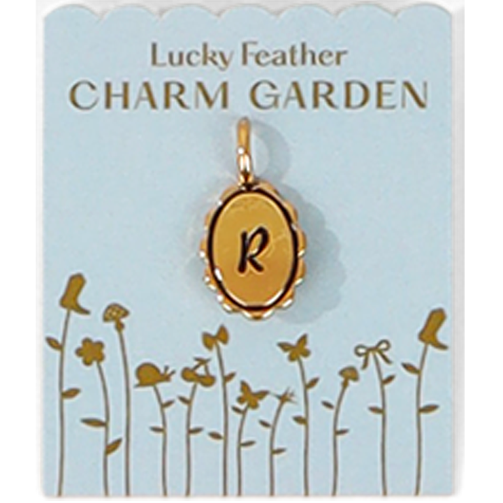 A gold charm with the letter R on a 'Lucky Feather Charm Garden' display card.