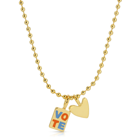 A gold ball chain necklace with a 'VOTE' charm and a heart charm.