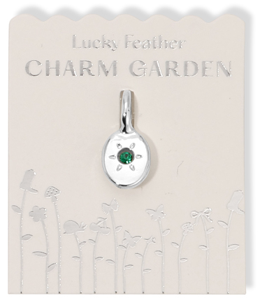 Silver charm pendant with a green gem on a "Lucky Feather Charm Garden" card with floral designs.