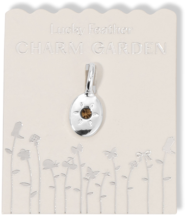 Silver charm pendant with a brown stone on a "Lucky Feather Charm Garden" card with silver flower designs.