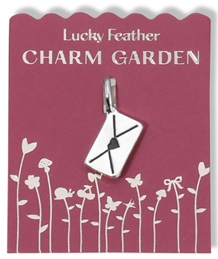A "Lucky Feather Charm Garden" charm of an envelope with a heart on it is displayed on a pink scalloped card with silver flower and garden designs.