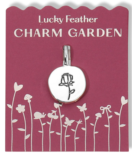 A Lucky Feather "Charm Garden" pendant with a rose design on a card with a garden illustration.