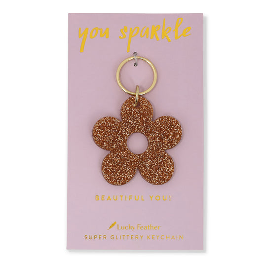 A flower-shaped glittery keychain on a pink card that says 'You sparkle' and 'Beautiful You!'.