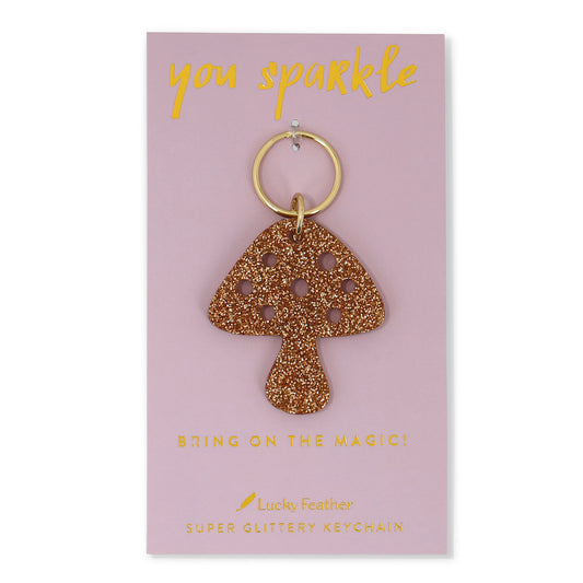 A glittery mushroom-shaped keychain on a pink card.