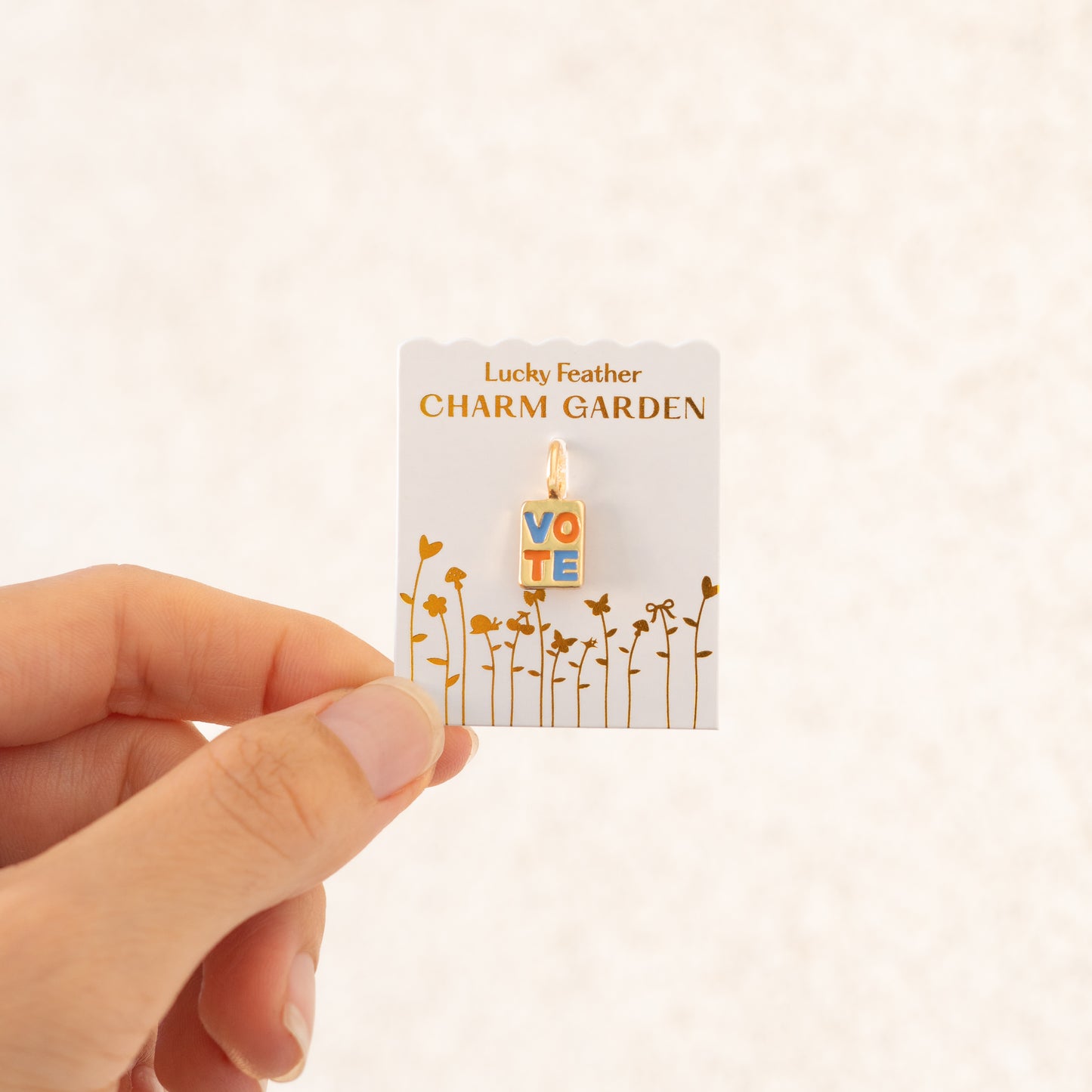 A hand holds a 'Lucky Feather Charm Garden' card with a 'VOTE' charm attached.