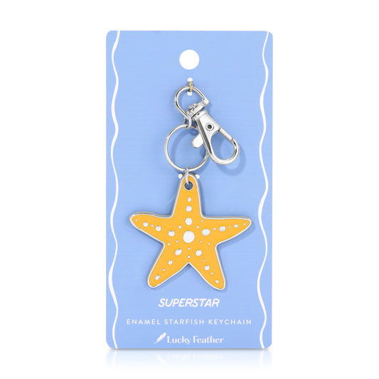 A yellow starfish enamel keychain hangs on a blue card.