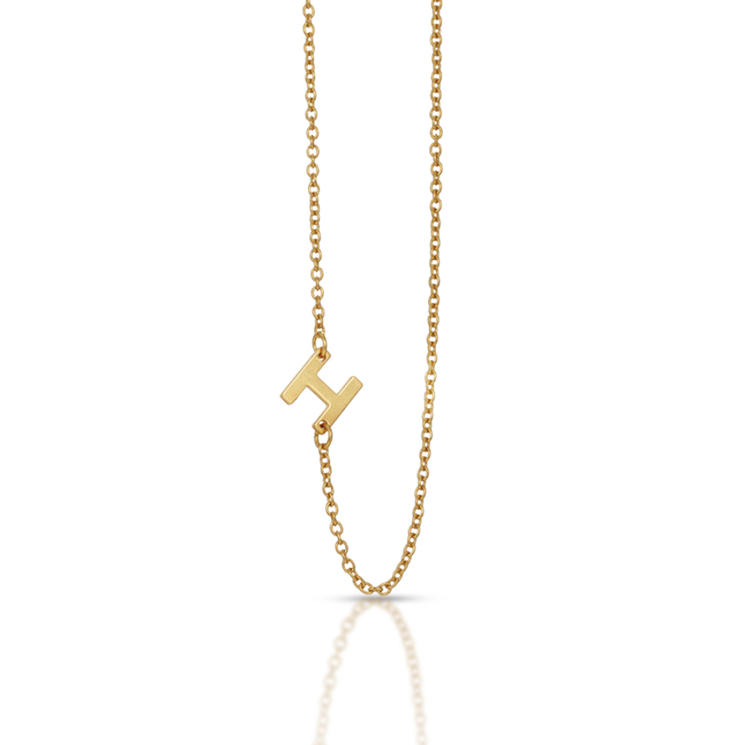 A gold chain necklace has a letter "H" pendant.