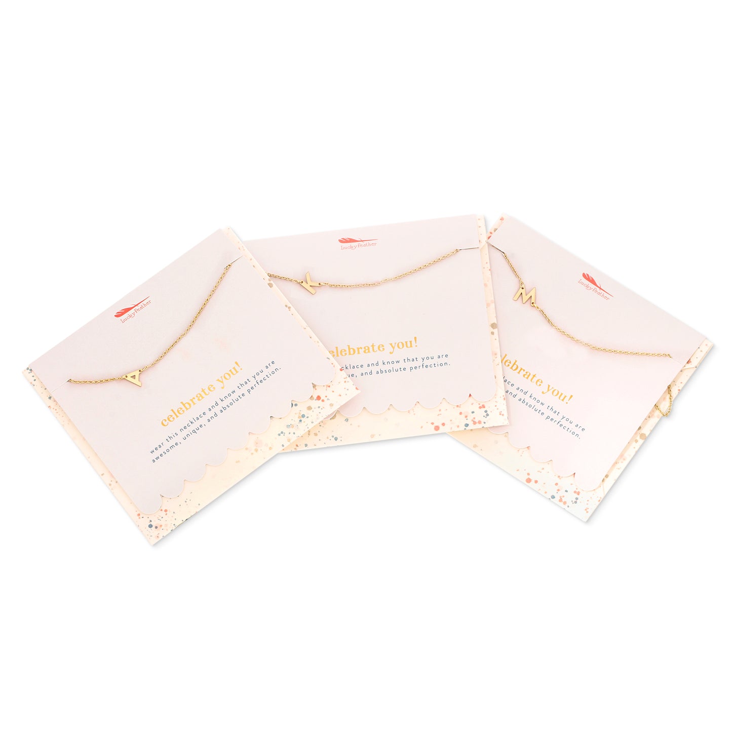Three gold initial necklaces on gift cards are angled and displayed on a white background.