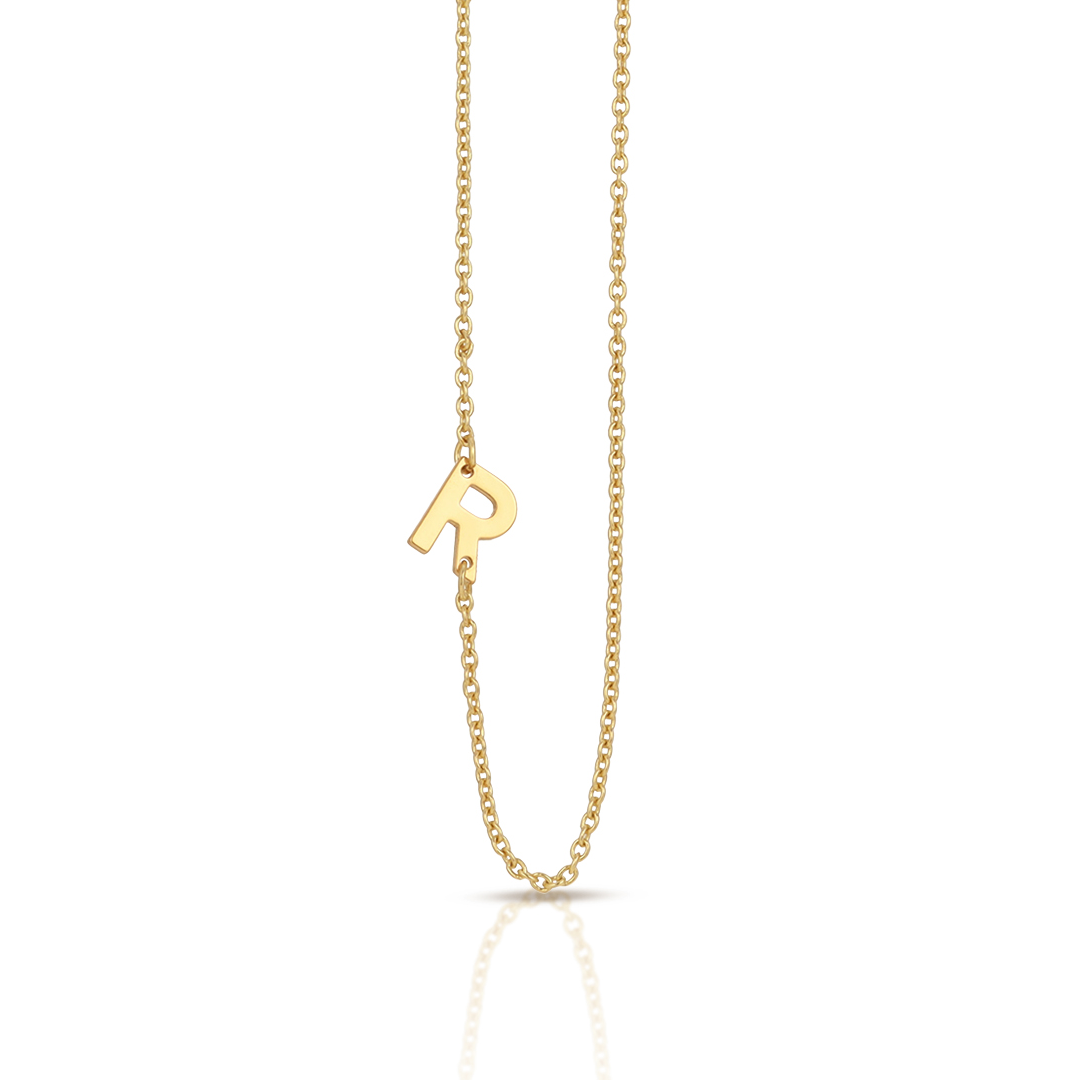 A gold necklace features an "R" pendant.
