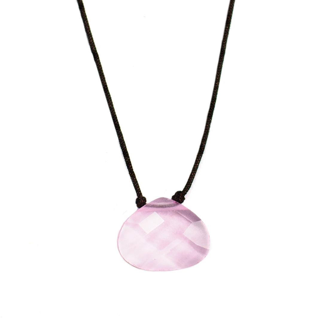 A necklace with a pink, faceted gemstone pendant hangs on a dark cord against a white background.