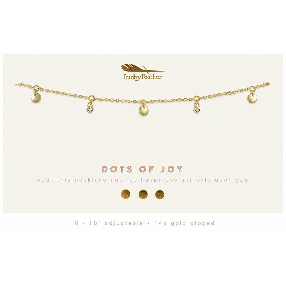 Close-up of a gold-toned "Lucky Feather" necklace with round and crystal charms, displayed on a card that reads "DOTS OF JOY."