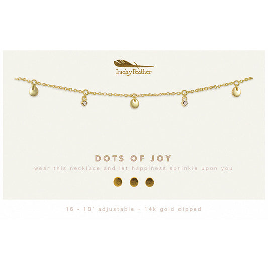 Close-up of a gold-toned 'Lucky Feather' necklace with round and crystal charms, displayed on a card that reads 'DOTS OF JOY.'