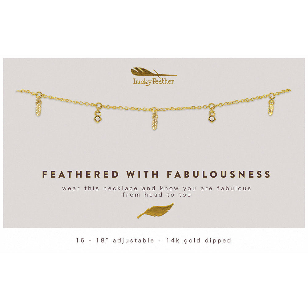 A 14k gold dipped necklace with feather and gem pendants on a display card.
