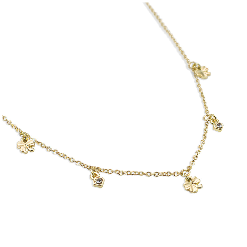 A delicate gold necklace with clover and gem charms is displayed on a white background.