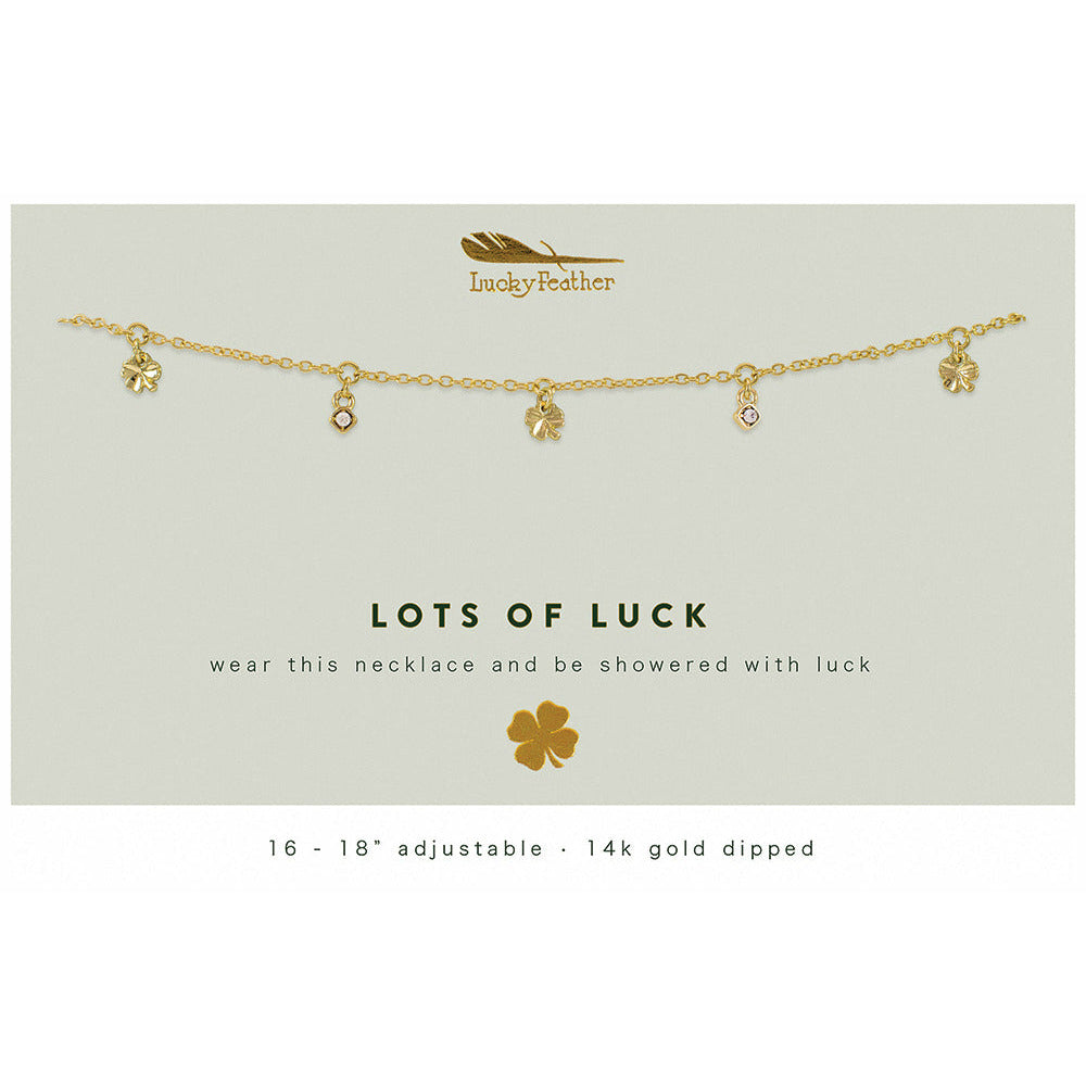 A gold-colored necklace with clover and jewel charms is displayed on a card that reads "Lots of Luck".