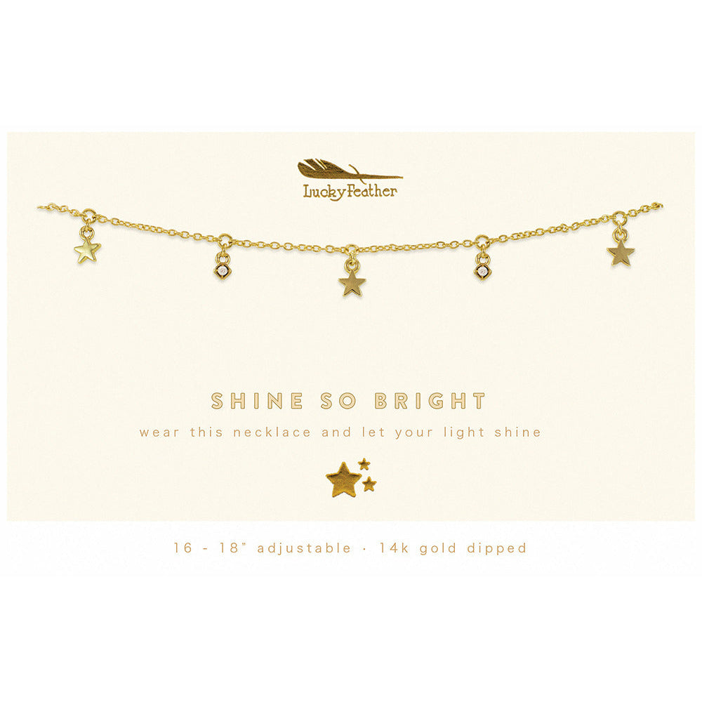 A gold-colored chain necklace with star and gem pendants, displayed on a card that says "Shine So Bright".