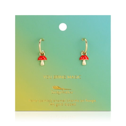 Gold hoop earrings with red and white mushroom charms are displayed on a green and yellow gradient card.