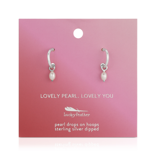 Two silver hoop earrings with pearl drops displayed on a pink branded card.