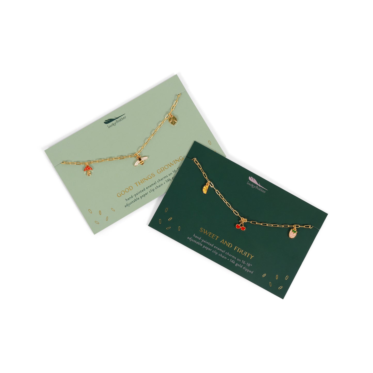 Two charm necklaces on cards, one with botanical charms and the other with fruit charms.