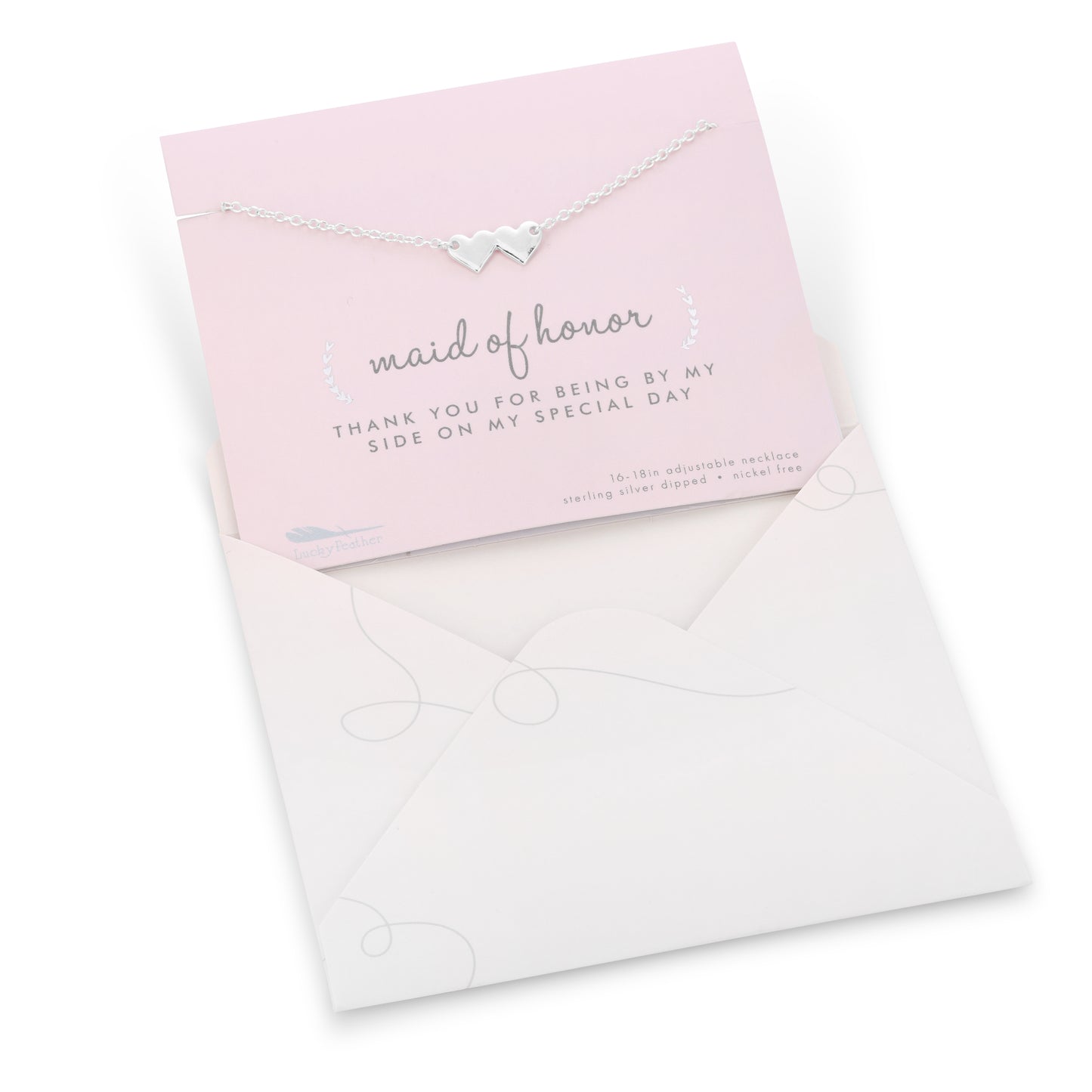 A silver necklace with two heart pendants is displayed on a "maid of honor" thank you card inside a light-colored envelope.