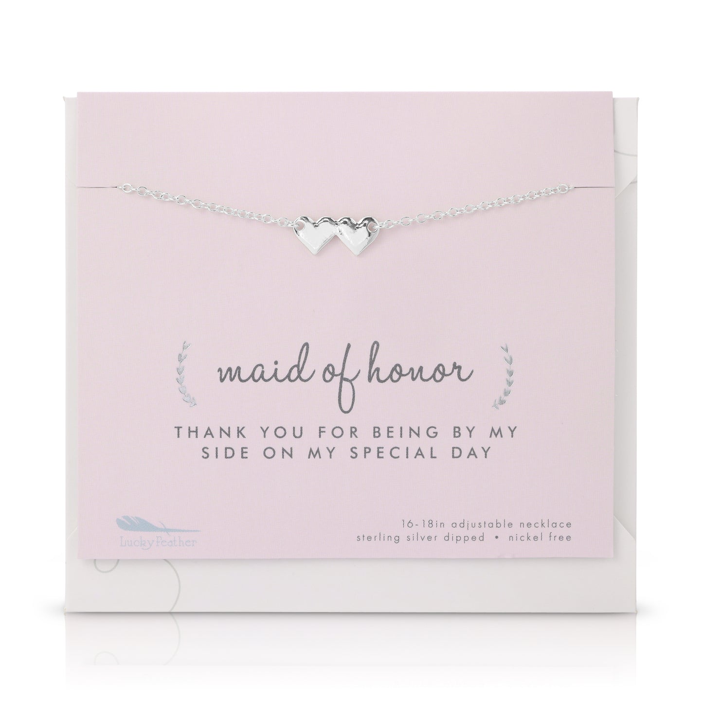 A silver necklace with two hearts is displayed on a pink card with "maid of honor" printed on it.