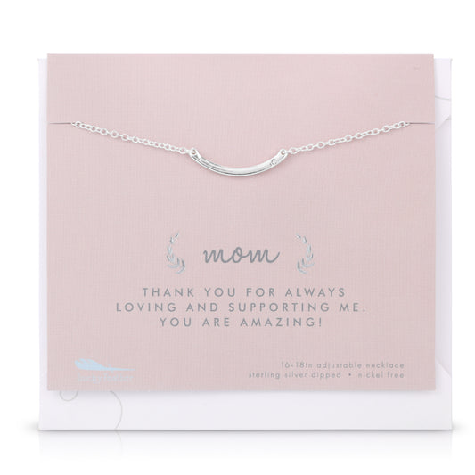 A silver-colored necklace with a curved bar pendant is displayed on a pink card with the words 'mom,' and 'THANK YOU FOR ALWAYS LOVING AND SUPPORTING ME. YOU ARE AMAZING!'