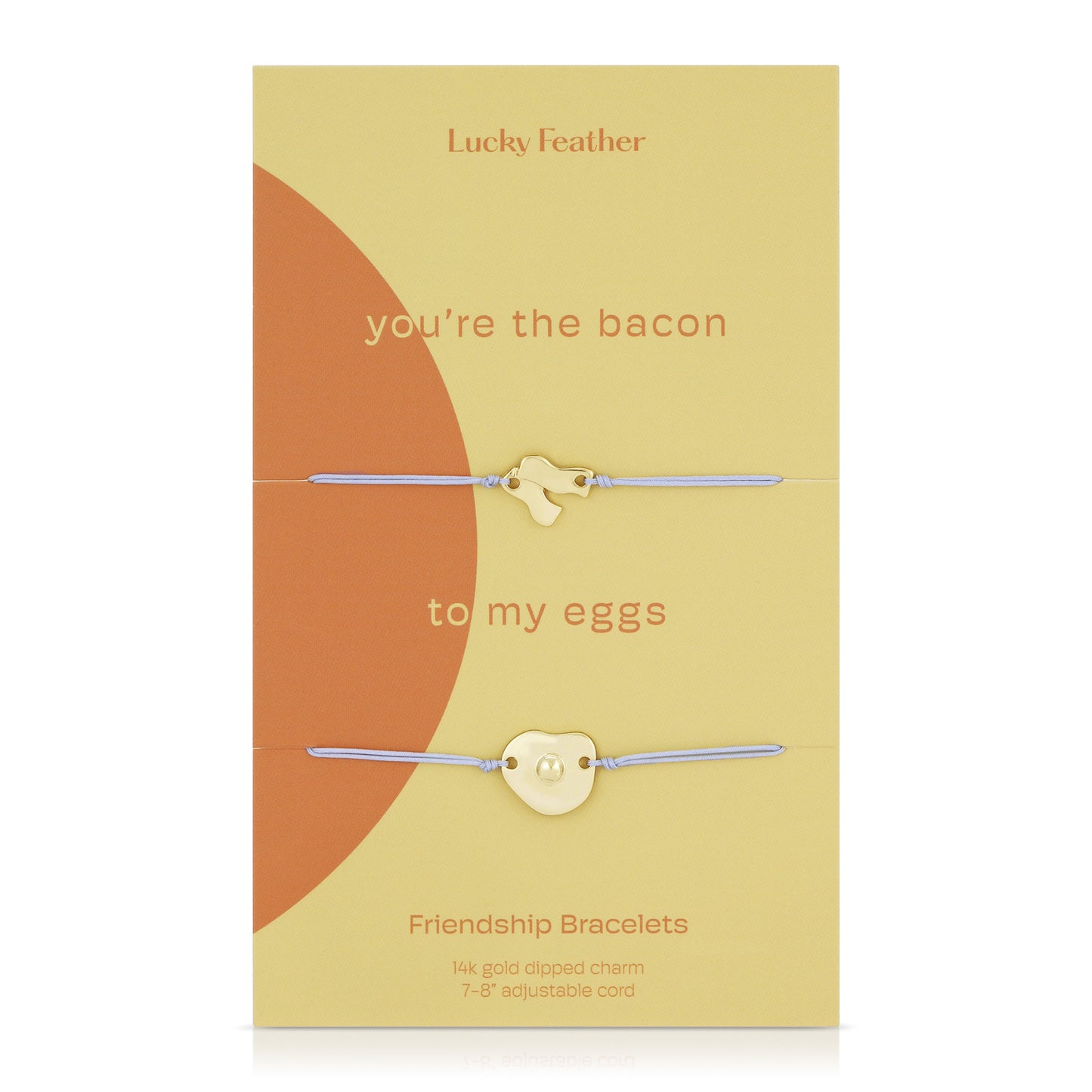 Two "Lucky Feather" friendship bracelets with gold-dipped bacon and egg charms on adjustable cords, presented on a decorative card with the text "you're the bacon to my eggs".
