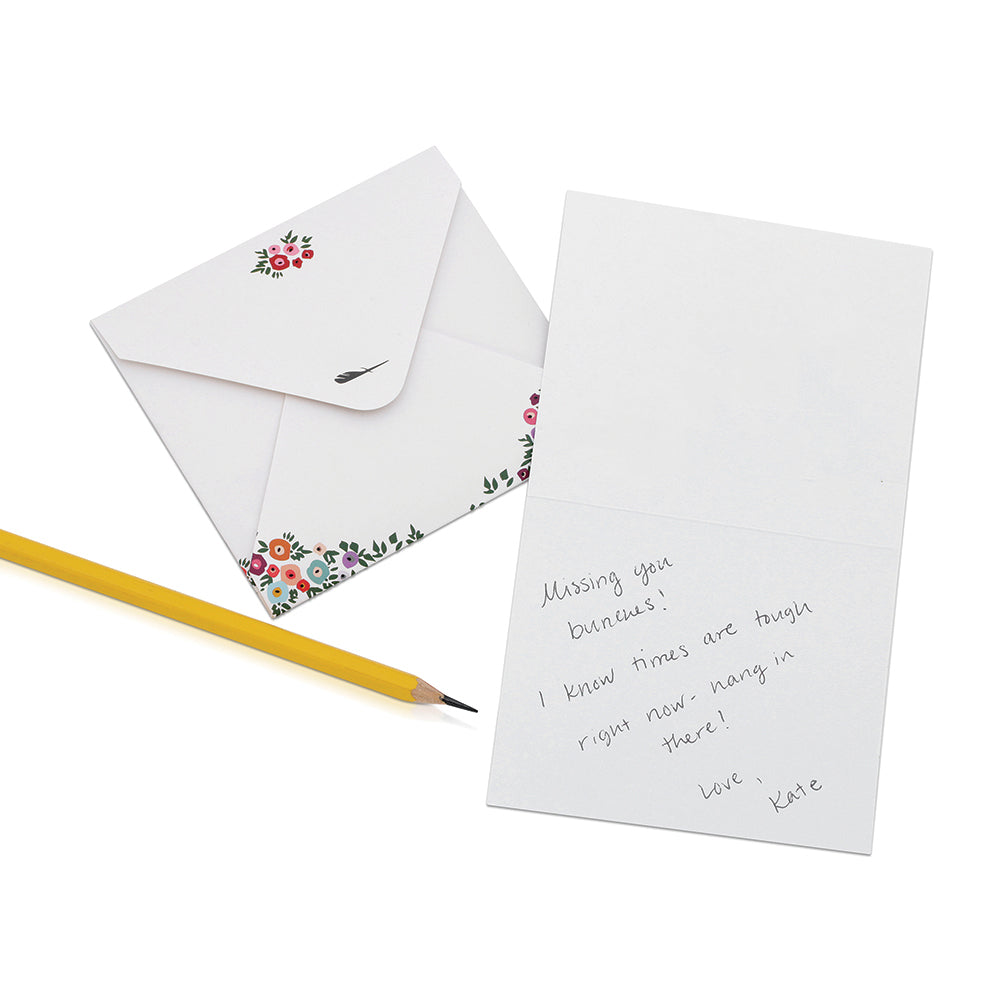 A floral-decorated envelope, a greeting card with a handwritten message, and a pencil are displayed.
