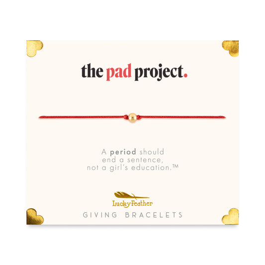 Promotional card for "The Pad Project" by Lucky Feather Giving Bracelets, featuring a red string bracelet with a gold bead.