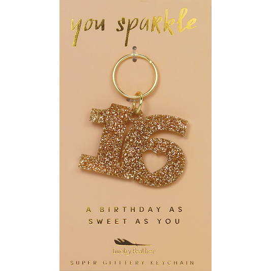 A glittery number 16 keychain hangs on a card that reads 'you sparkle' and 'a birthday as sweet as you.'