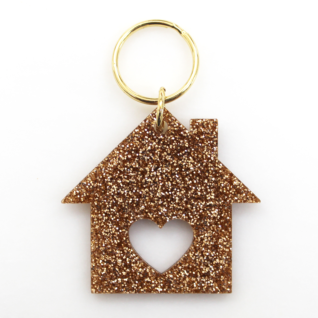 A sparkly bronze house-shaped keychain with a heart cut-out on a white background.