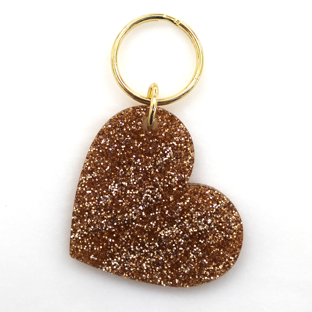 A golden glittery heart-shaped keychain on a white background.
