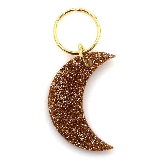 A gold glitter crescent moon keychain with a gold ring on a white background.