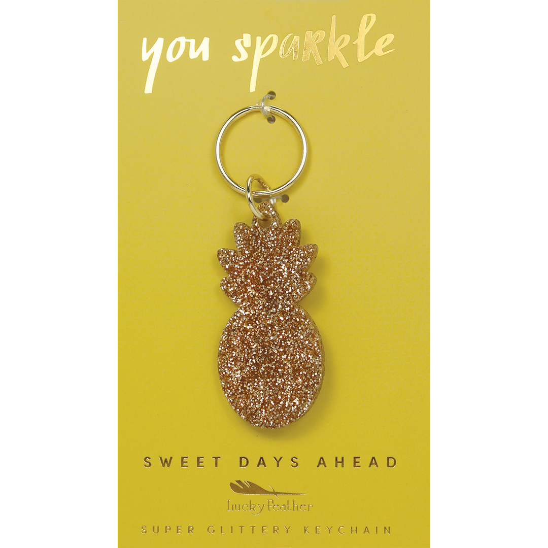 A pineapple-shaped keychain with glitter on a yellow card.