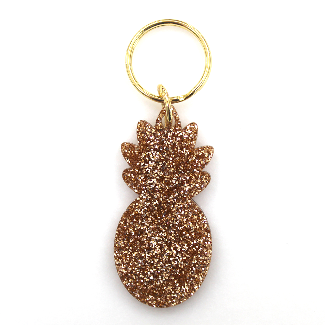 A gold glitter pineapple-shaped keychain on a white background.