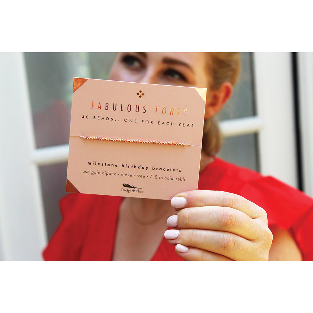 A woman holds up a 'Fabulous Forty' bracelet.