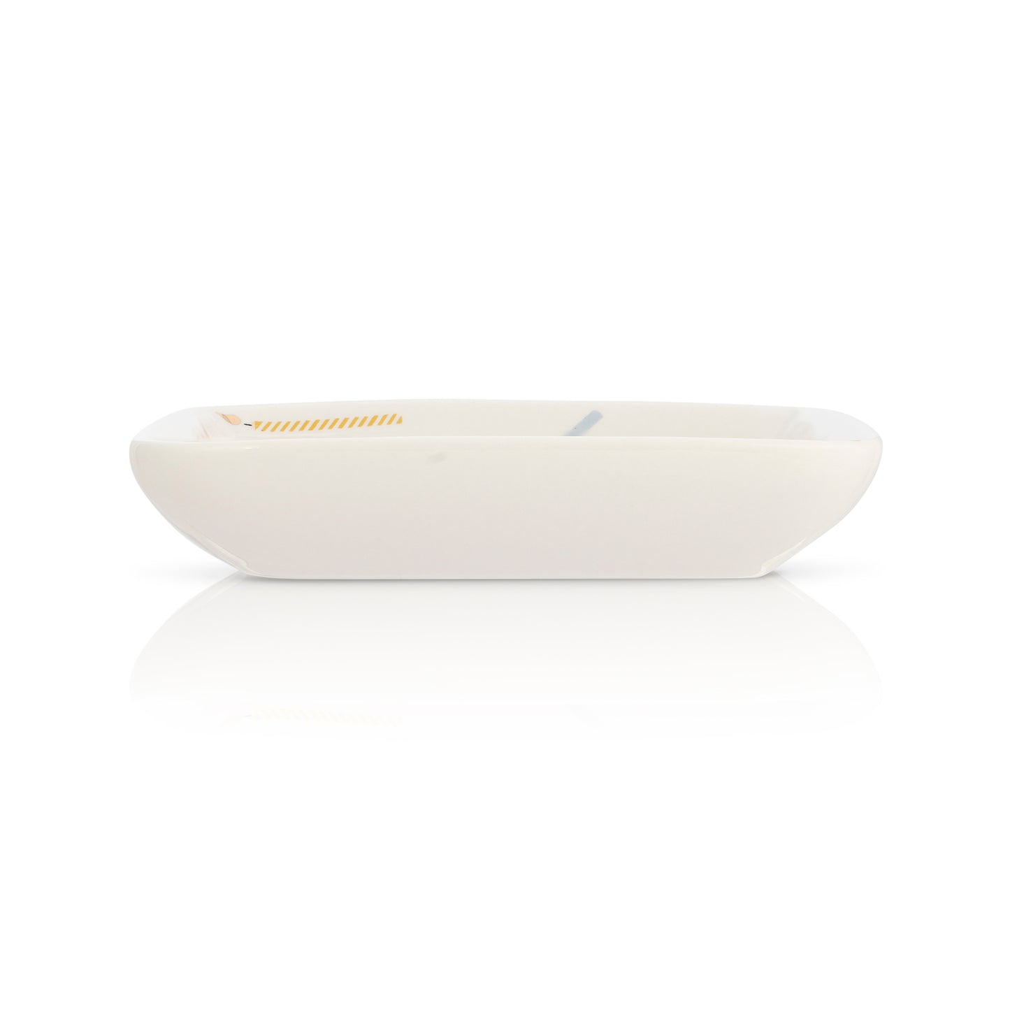 A small, rectangular, off-white dish with minimal design sits on a white surface, casting a reflection.