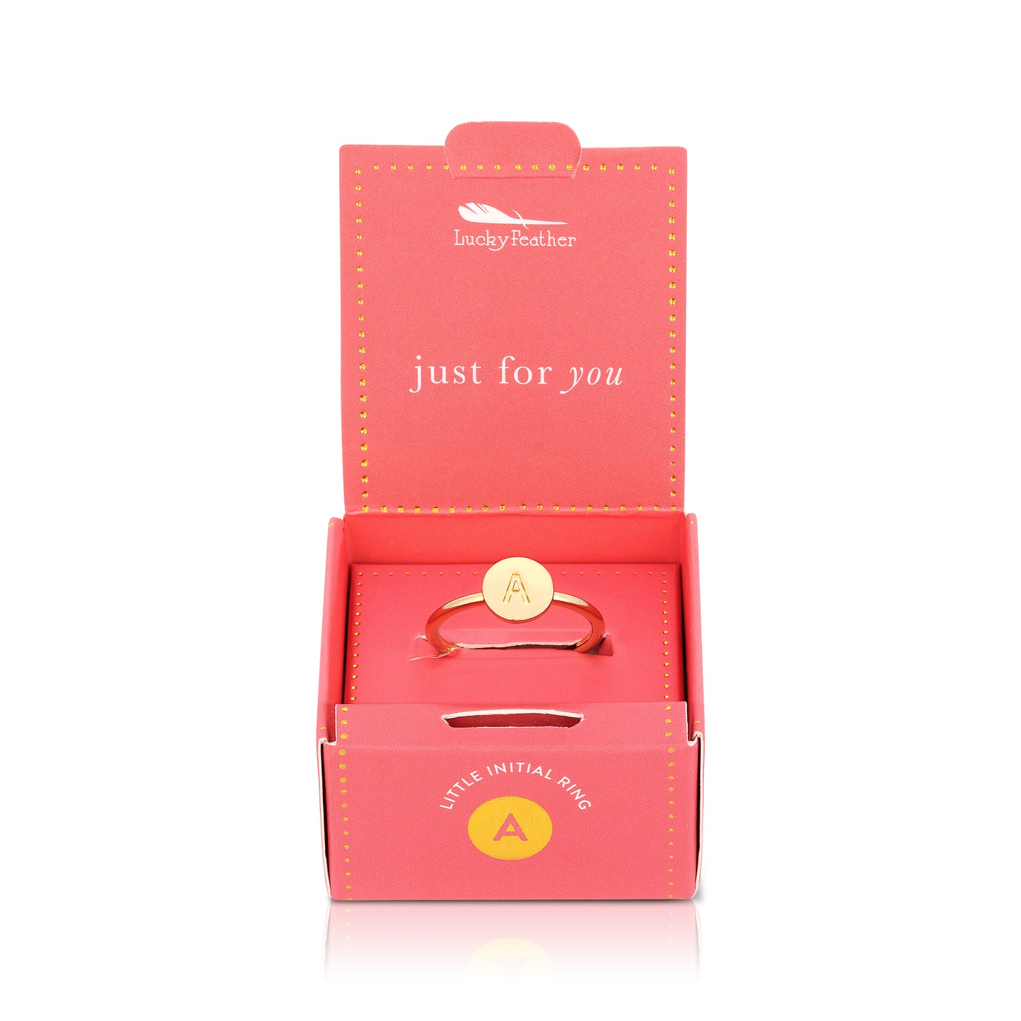A gold ring with the letter "A" inside a circular setting sits inside a pink "Lucky Feather" box.