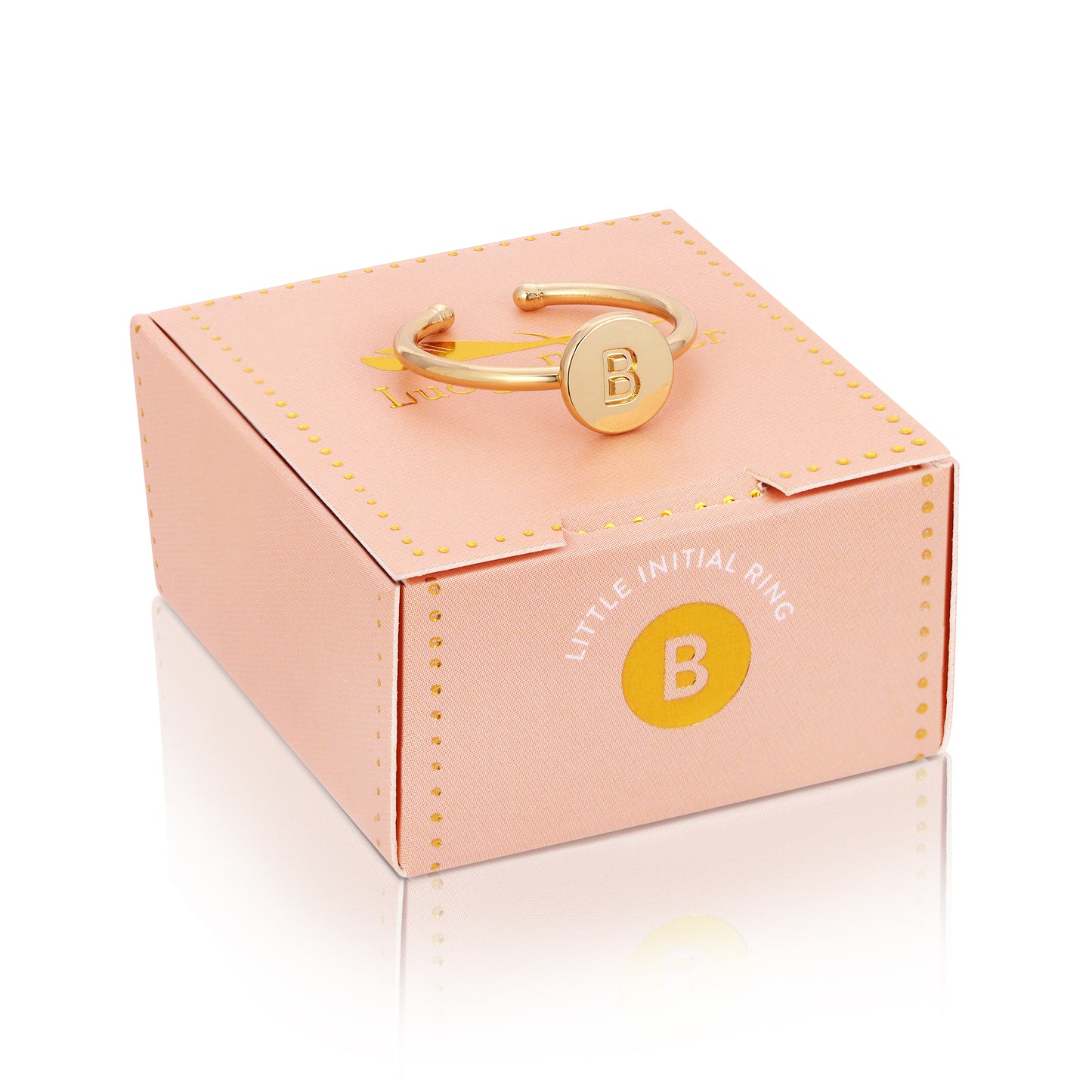 A gold-colored ring with the letter "B" rests on top of a pink box with "Little Initial Ring" printed on it.