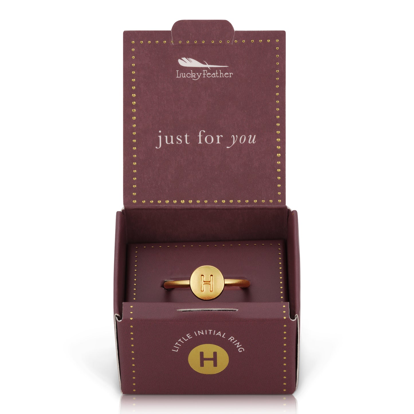 An open "Lucky Feather" ring box reveals a gold-colored initial ring with the letter H.
