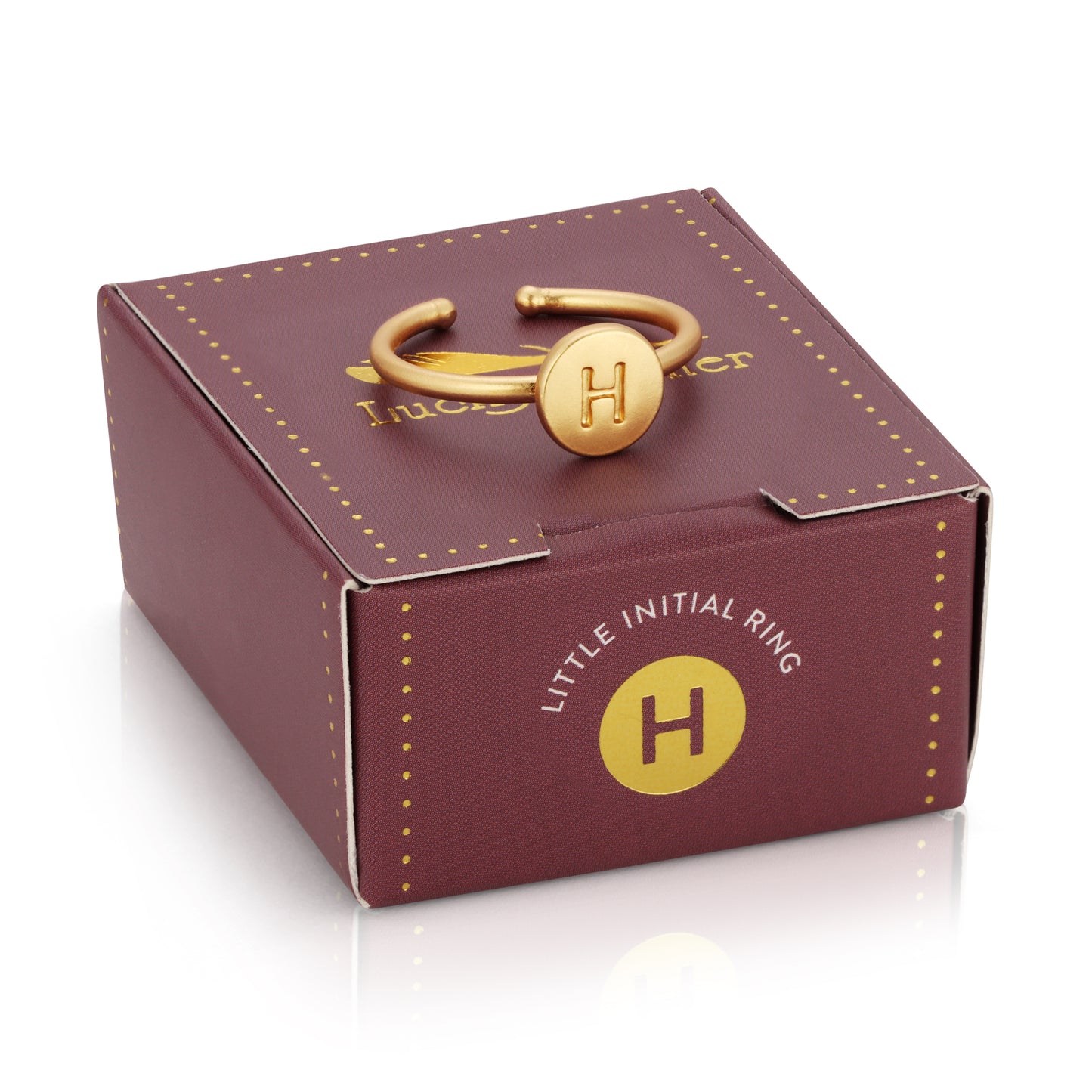 A gold ring with the initial "H" sits atop a burgundy gift box with gold detailing.