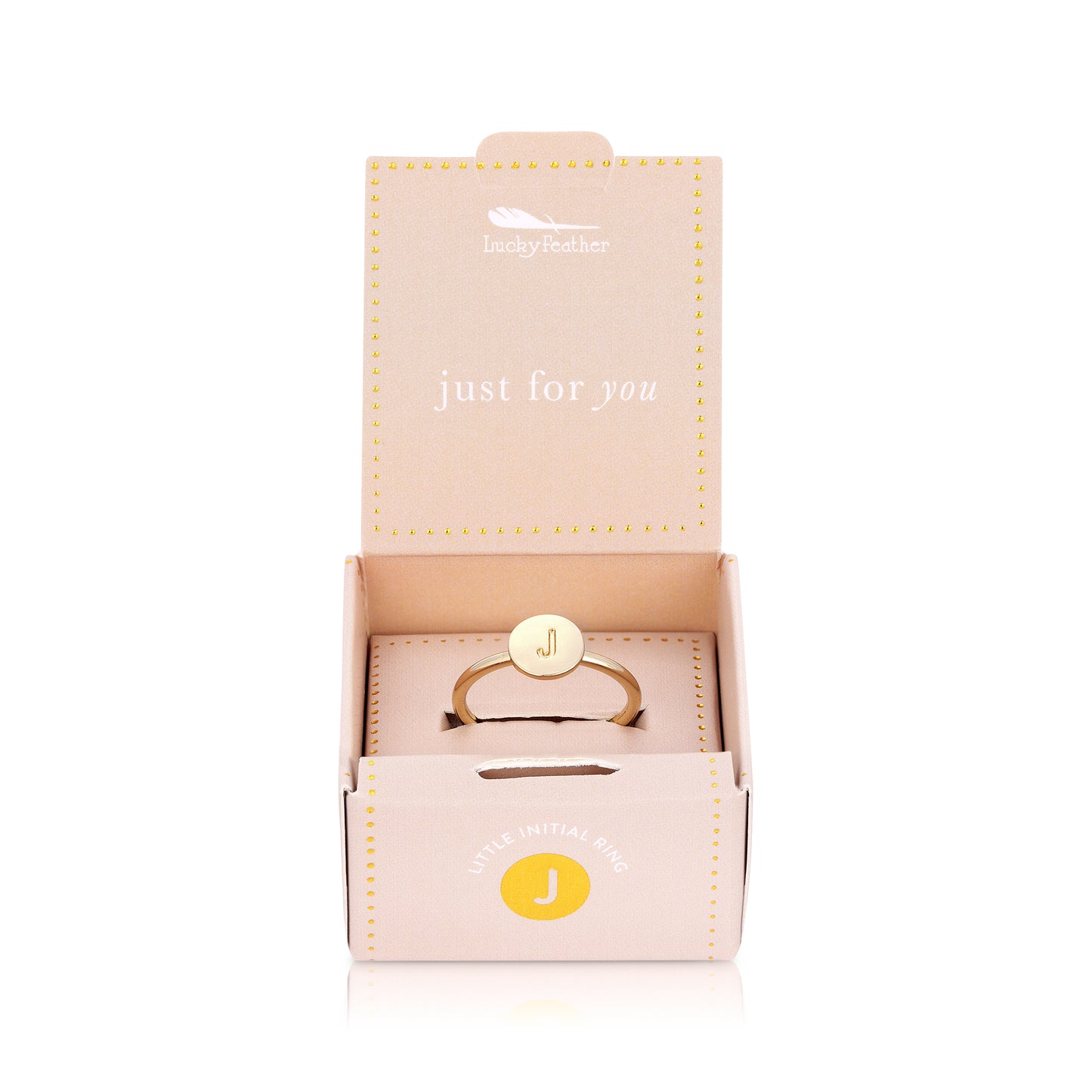 A gold-colored ring with the letter "J" on the face sits inside an open, light pink box with the text "Lucky Feather" and "Little Initial Ring".