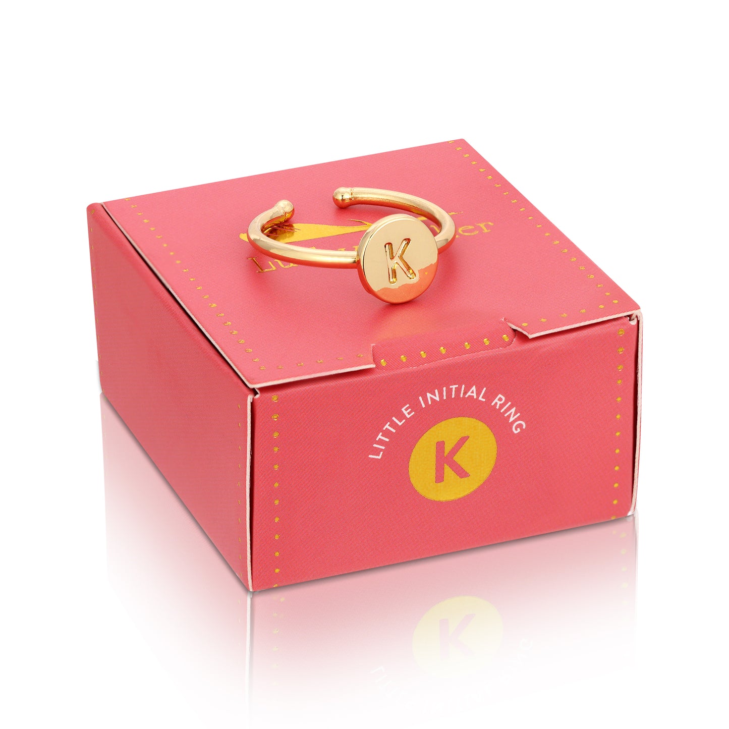 A gold ring with the letter K sits on top of a pink gift box.