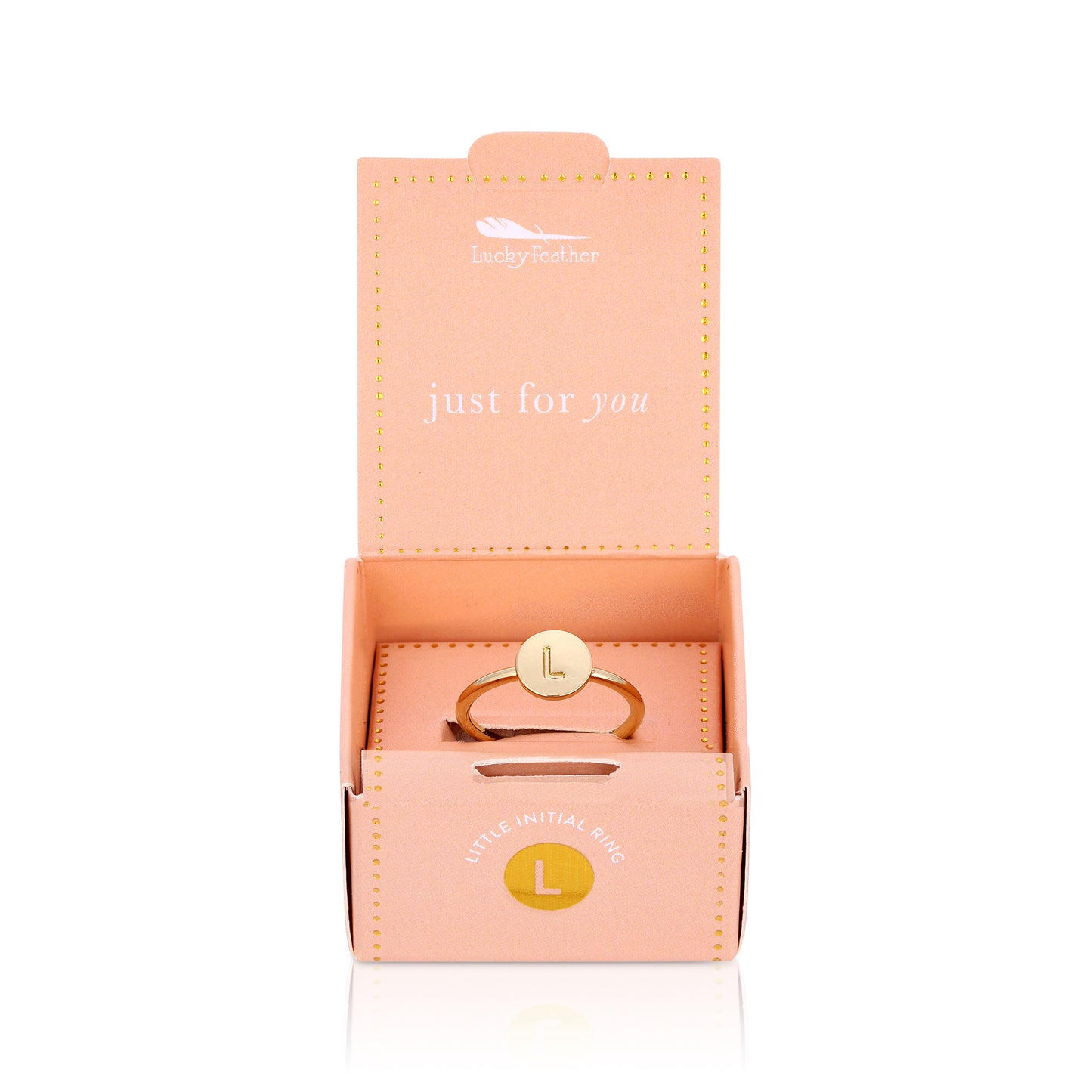A gold-tone ring with the letter L on a round face sits in its open pink gift box.